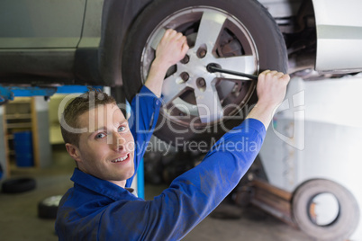 Male mechanic changing car tire