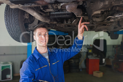 Male repairman examining under car