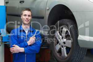 Male mechanic standing by car