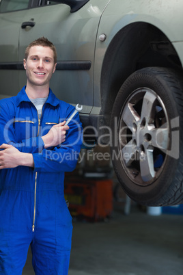 Mechanic with hand tool standing by car