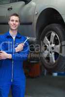 Mechanic with hand tool standing by car