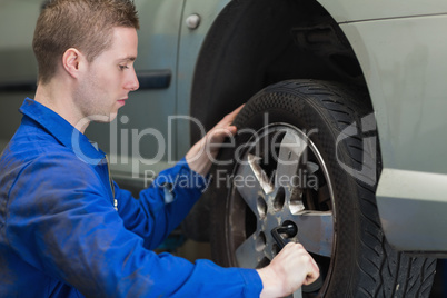Male mechanic changing car wheel