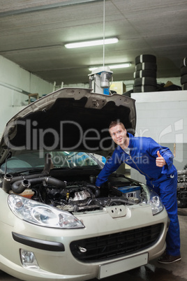 Mechanic by car giving thumbs up gesture Mechanic by car giving thumbs up gesture