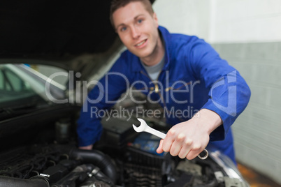 Auto mechanic with spanner repairing car
