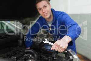 Auto mechanic with spanner repairing car