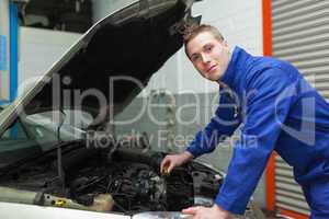 Confident mechanic checking car engine oil