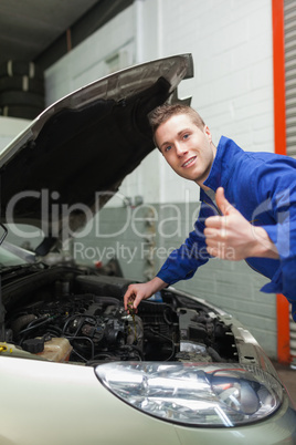Auto mechanic by car gesturing thumbs up