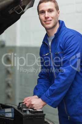 Happy male mechanic with car battery