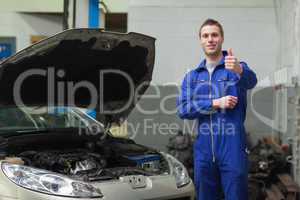 Mechanic by car giving thumbs up gesture