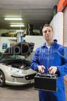 Confident auto mechanic with car battery