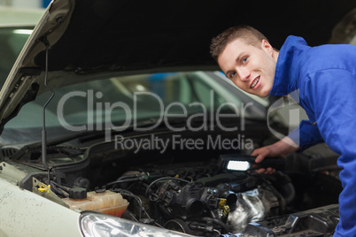 Confident repairman examining car engine