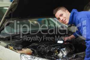 Confident repairman examining car engine