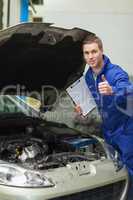Mechanic by car showing thumbs up