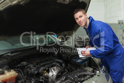 Mechanic with clipboard by car