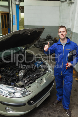 Mechanic by car showing thumbs up sign