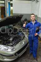 Mechanic by car showing thumbs up sign