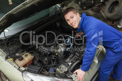 Happy mechanic examining car engine