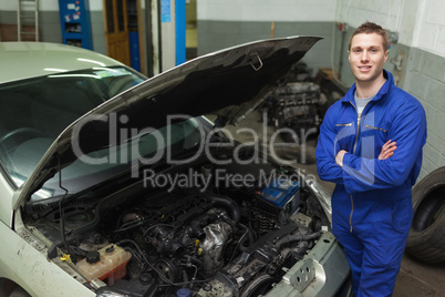Confident repairman by car with open hood