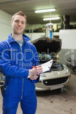 Happy auto mechanic writing on clipboard