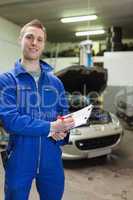 Happy auto mechanic writing on clipboard