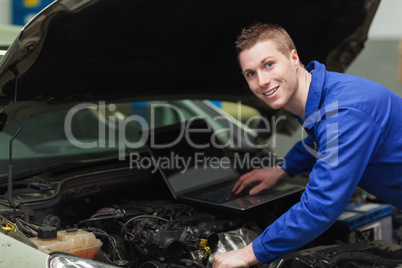 Happy mechanic using laptop