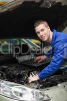Car mechanic with laptop checking engine