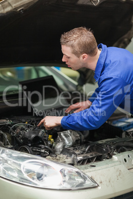 Repairman with laptop checking car engine