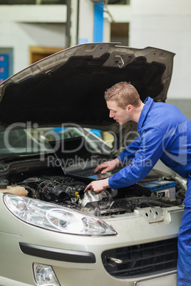 Auto mechanic with laptop repairing car