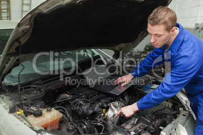 Mechanic with laptop repairing car