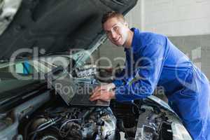 Male auto mechanic using laptop