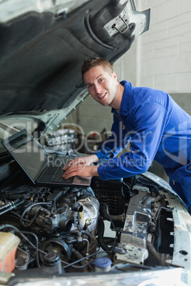 Mechanic using laptop on car engine