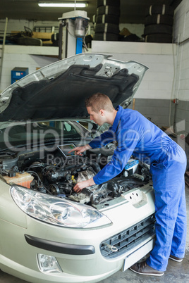 Male mechanic analyzing car engine