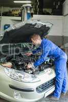 Male mechanic analyzing car engine