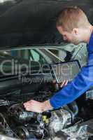 Repairman with tablet pc repairing car engine