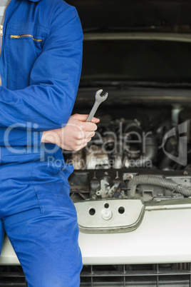 Mechanic with spanner by car