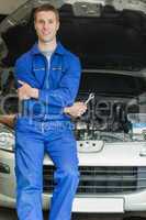 Happy mechanic leaning on breakdown car