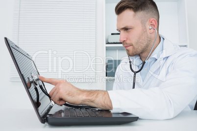 Hardware professional examining laptop with stethoscope
