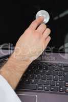 Hand examining laptop screen with stethoscope