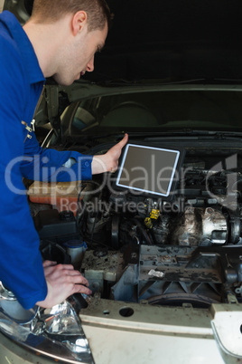 Mechanic by car holding tablet pc