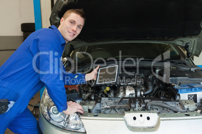 Mechanic by car holding digital tablet