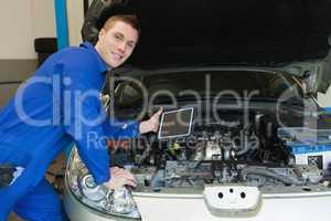 Mechanic by car holding digital tablet