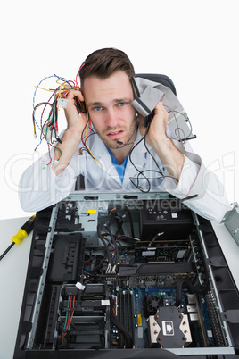 Portrait of tired young it professional with cables in hands