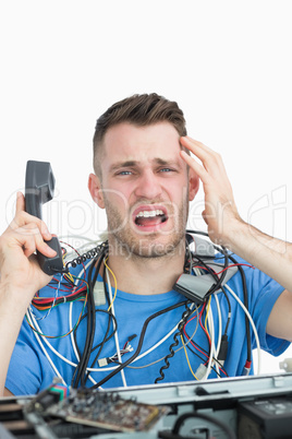 Portrait of frustrated computer engineer on call in front of ope