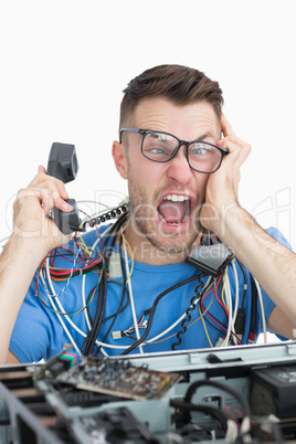 Frustrated computer engineer screaming while on call in front of