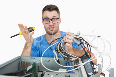 Portrait of confused it professional with screw driver and cable