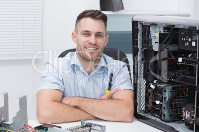 Smiling hardware professional sitting by an open cpu