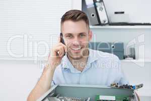Portrait of smiling computer engineer on call in front of open c