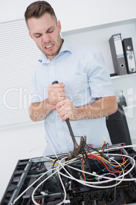 Frustrated man using hammer to pull out wires from cpu