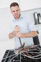 Portrait of frustrated man using hammer to pull out wires from c