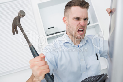 Frustrated man hitting computer monitor with hammer